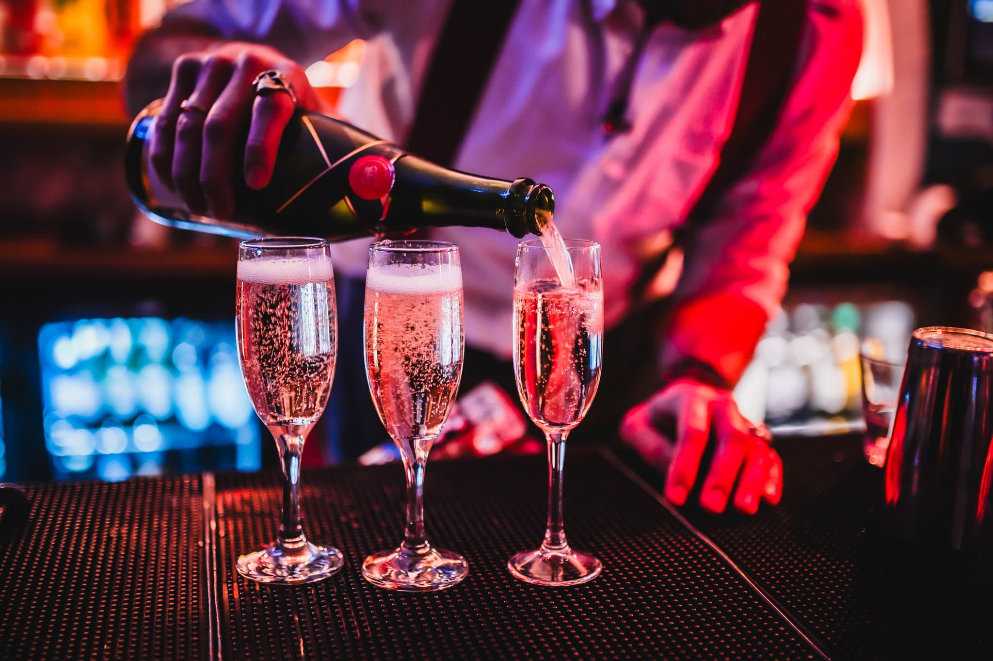 A bartender poring three glasses of prosecco at the bar