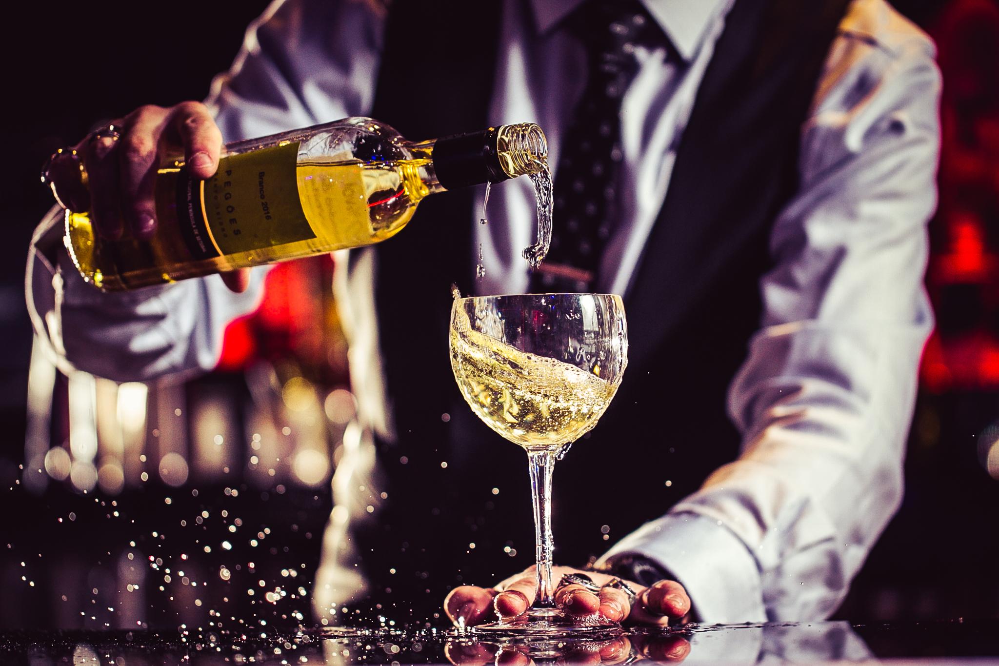 A bartender pouring a glass of white wine